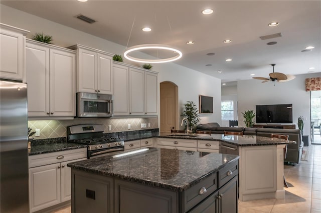 kitchen featuring white cabinets, stainless steel appliances, light tile patterned flooring, ceiling fan, and a kitchen island