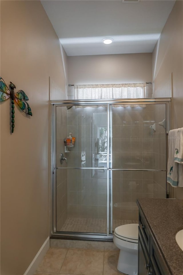 bathroom featuring tile patterned flooring, vanity, toilet, and walk in shower