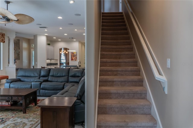 staircase with ceiling fan and ornate columns