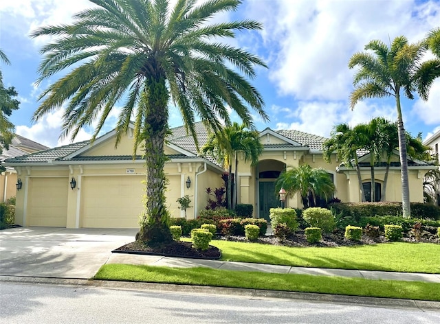 view of front of house with a tile roof, driveway, an attached garage, and stucco siding