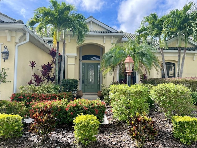 property entrance featuring a tiled roof and stucco siding