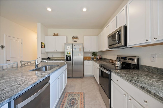 kitchen featuring sink, light tile floors, white cabinets, dark stone countertops, and stainless steel appliances