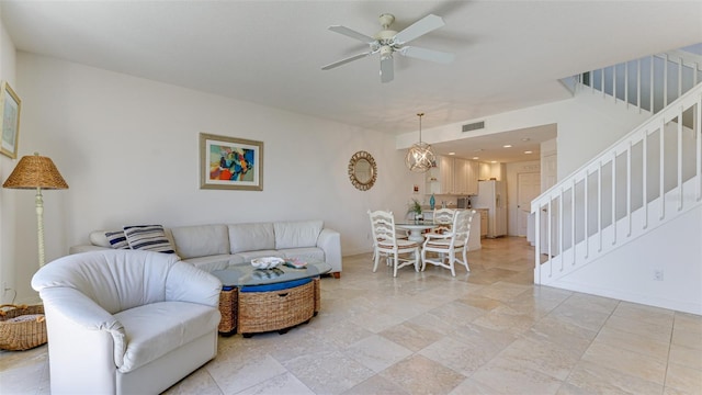 tiled living room with ceiling fan with notable chandelier