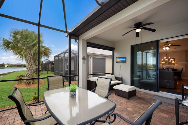 sunroom with ceiling fan with notable chandelier and a water view