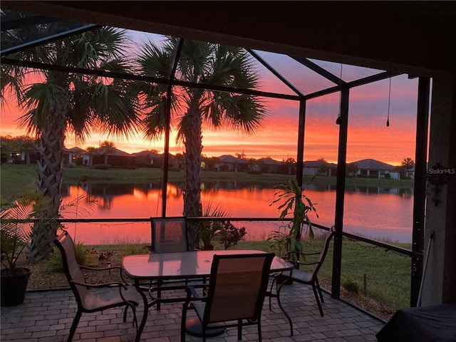 patio terrace at dusk featuring a lanai and a water view