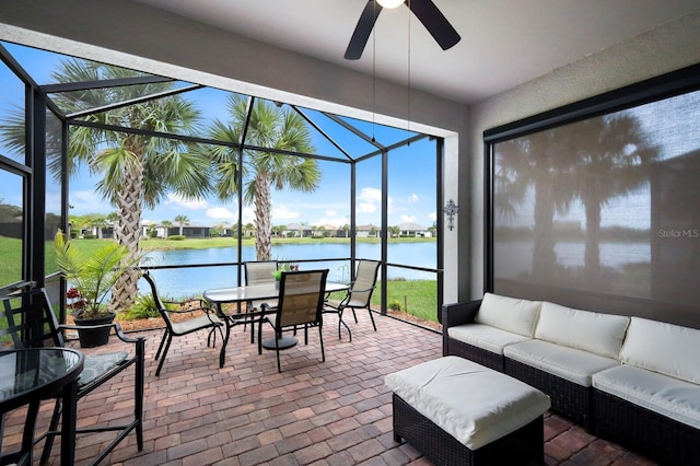 sunroom featuring ceiling fan and a water view