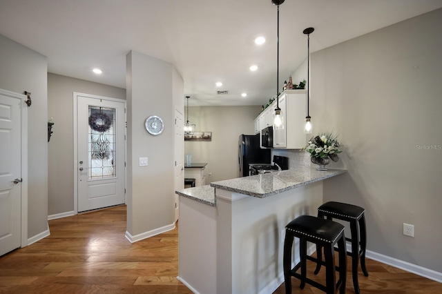 kitchen featuring a kitchen breakfast bar, kitchen peninsula, white cabinetry, and hanging light fixtures