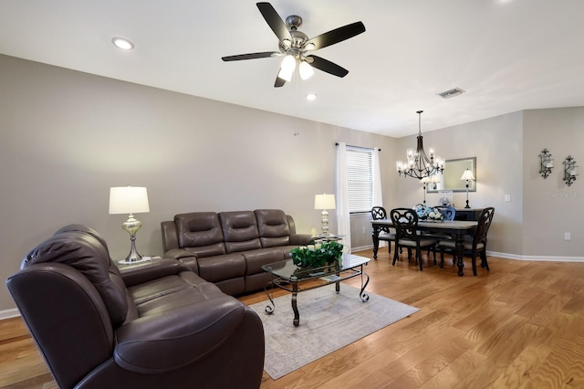 living room featuring ceiling fan with notable chandelier and light wood-type flooring