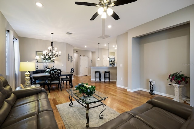 living room featuring light hardwood / wood-style floors and ceiling fan with notable chandelier