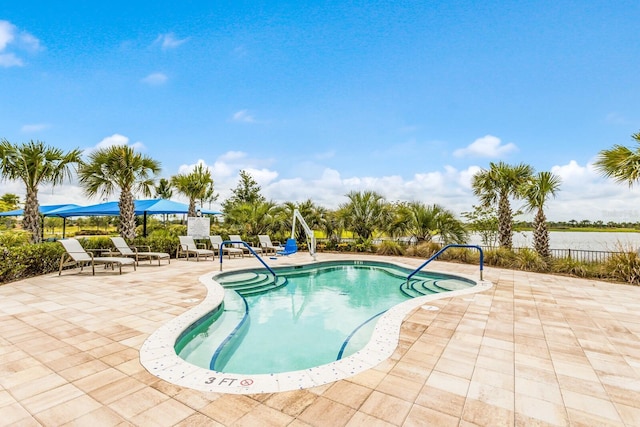 view of swimming pool with a patio area and a water view