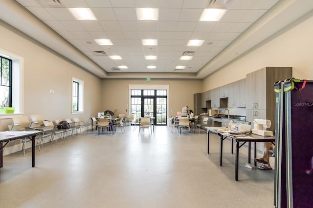 interior space with french doors, a towering ceiling, a drop ceiling, and sink