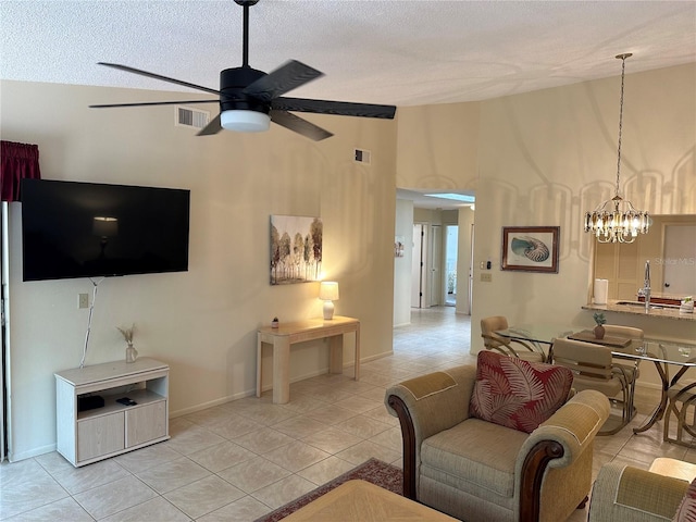 tiled living room featuring a textured ceiling, high vaulted ceiling, ceiling fan with notable chandelier, and sink