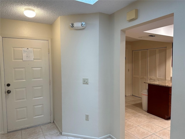 entrance foyer with a textured ceiling, light tile flooring, and a skylight