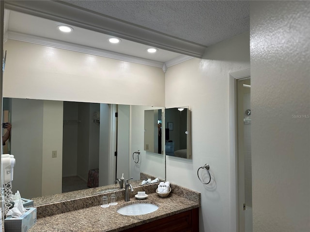 bathroom featuring a textured ceiling, ornamental molding, and vanity