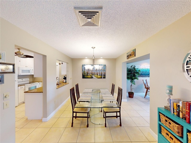 dining area featuring light tile patterned floors, a textured ceiling, and sink