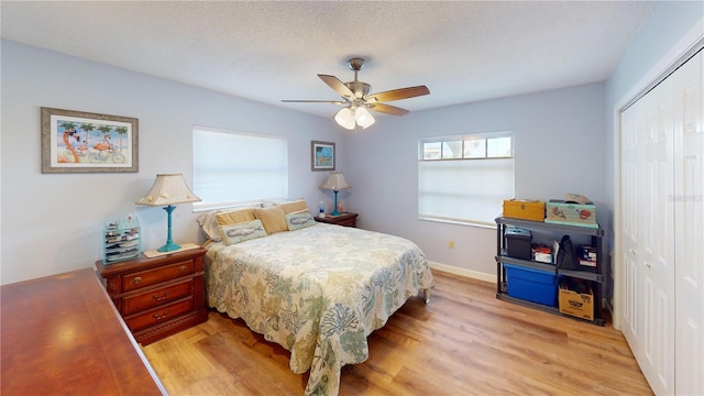 bedroom featuring a textured ceiling, light hardwood / wood-style flooring, a closet, and ceiling fan