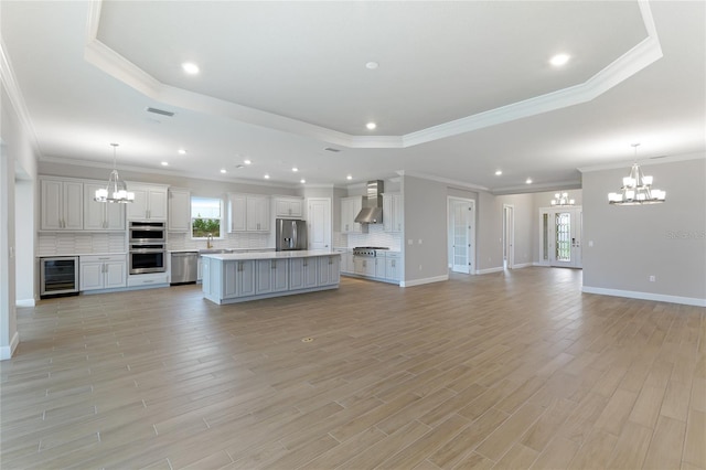 unfurnished living room with crown molding, beverage cooler, a raised ceiling, and a wealth of natural light