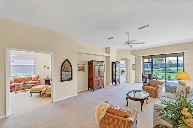 living room with light colored carpet, ceiling fan, and a wealth of natural light