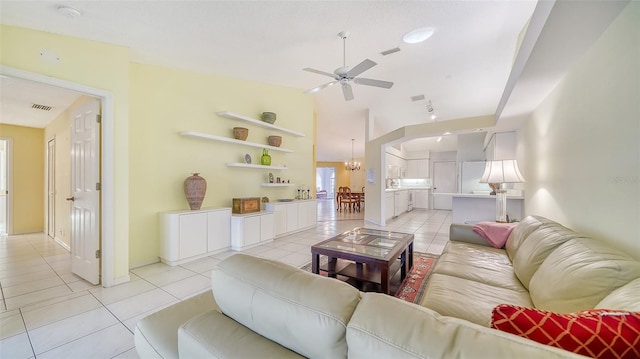 tiled living room with ceiling fan with notable chandelier