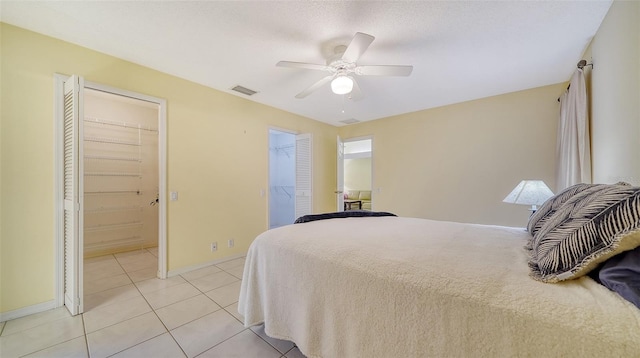 tiled bedroom with ensuite bathroom, a spacious closet, a closet, and ceiling fan