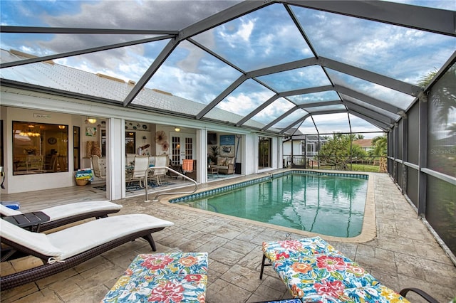 view of swimming pool featuring glass enclosure and a patio