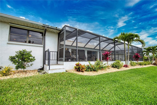 rear view of house with a lanai and a lawn