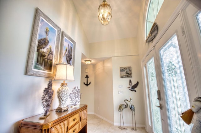 foyer entrance with light tile flooring, a chandelier, and high vaulted ceiling