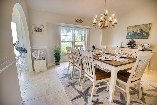 dining room featuring an inviting chandelier, vaulted ceiling, and light tile floors