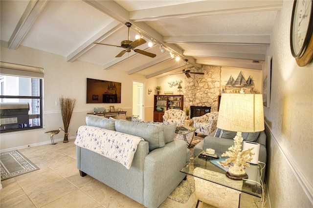 tiled living room featuring vaulted ceiling with beams, a stone fireplace, and ceiling fan