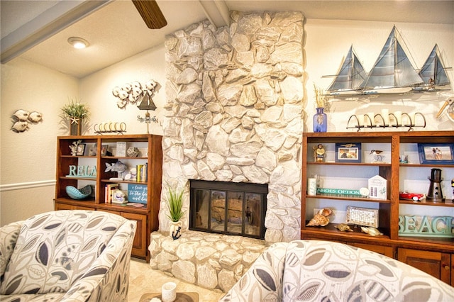 living room with a stone fireplace, ceiling fan, and lofted ceiling with beams