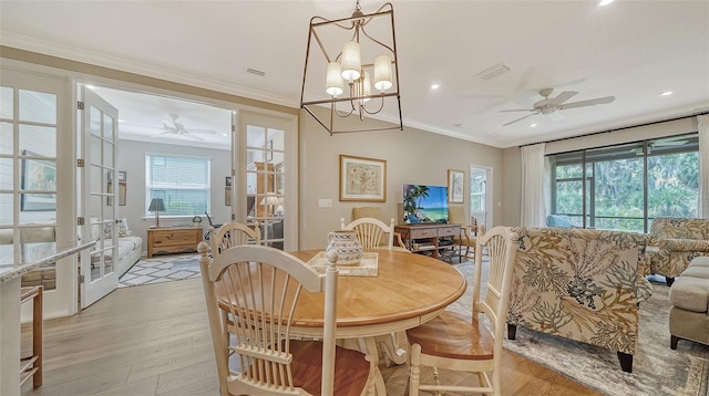 dining area featuring plenty of natural light, crown molding, light hardwood / wood-style floors, and ceiling fan with notable chandelier