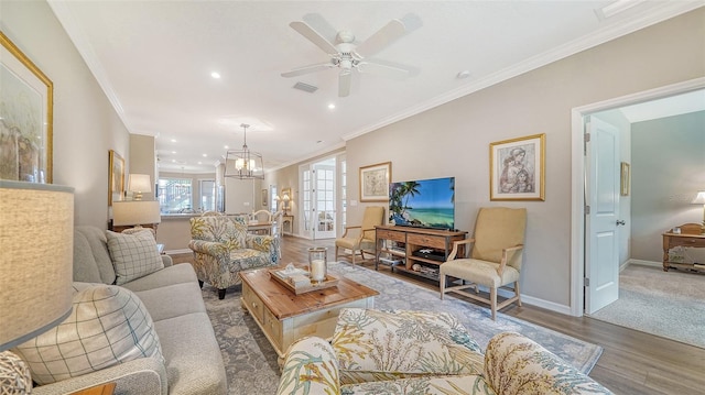 living room with carpet flooring, ceiling fan with notable chandelier, and ornamental molding