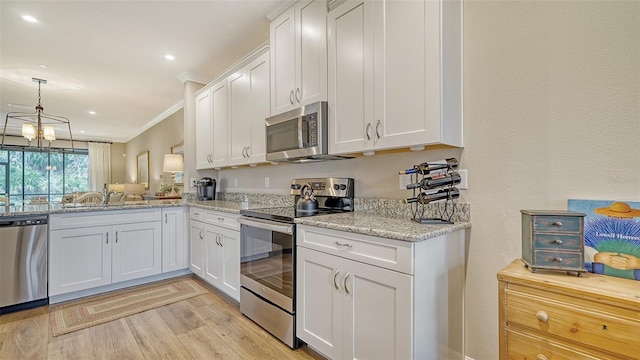 kitchen featuring ornamental molding, stainless steel appliances, white cabinetry, and an inviting chandelier