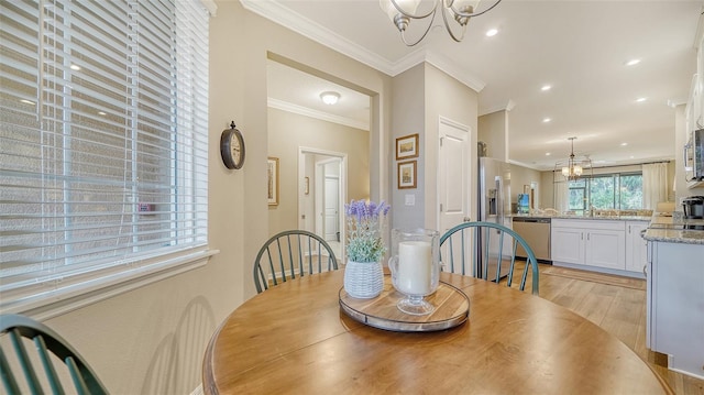 dining room with light hardwood / wood-style floors, ornamental molding, and a notable chandelier