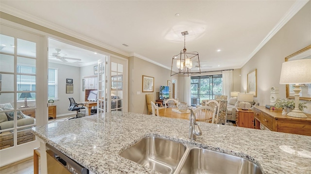 kitchen with ornamental molding, ceiling fan with notable chandelier, decorative light fixtures, and light stone counters