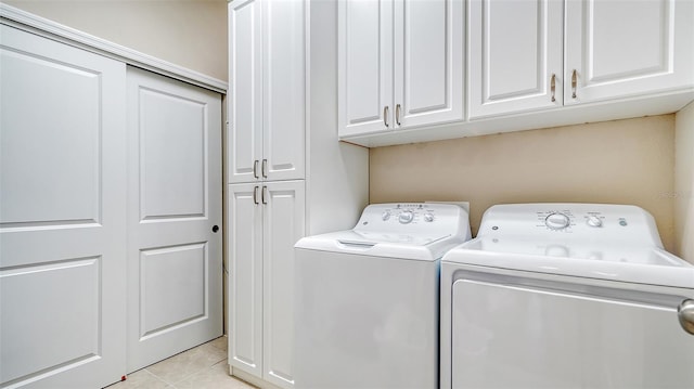 clothes washing area with light tile flooring, washing machine and dryer, and cabinets