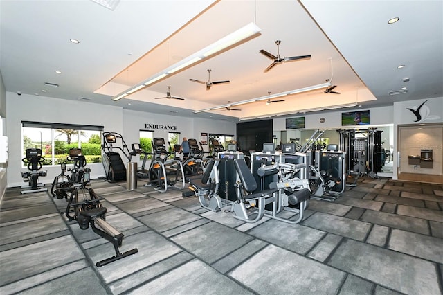 gym featuring a tray ceiling and ceiling fan