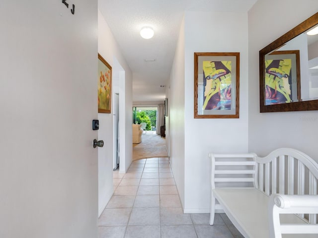 corridor featuring light colored carpet and a textured ceiling