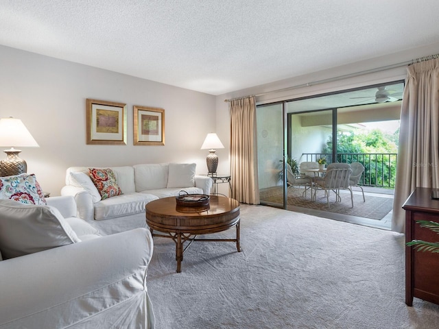 carpeted living room featuring ceiling fan and a textured ceiling