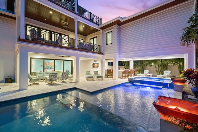 pool at dusk with pool water feature, a patio area, outdoor lounge area, an in ground hot tub, and ceiling fan