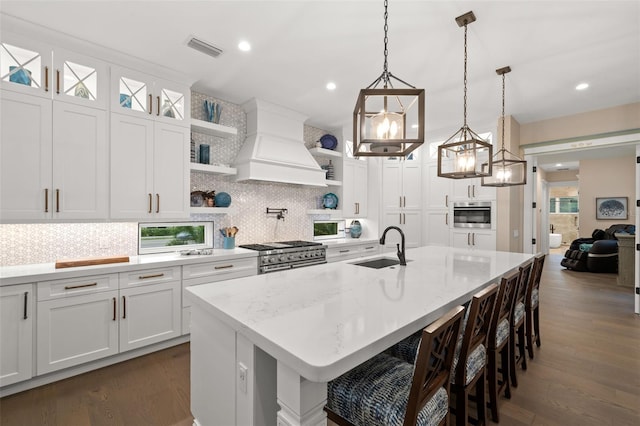 kitchen featuring pendant lighting, sink, white cabinets, custom exhaust hood, and stainless steel appliances