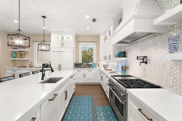 kitchen featuring sink, white cabinets, premium appliances, light stone countertops, and custom range hood