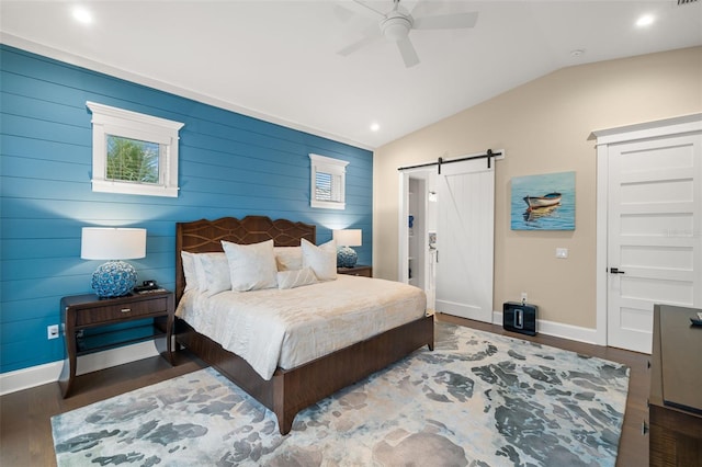 bedroom with ceiling fan, lofted ceiling, a barn door, and dark hardwood / wood-style flooring