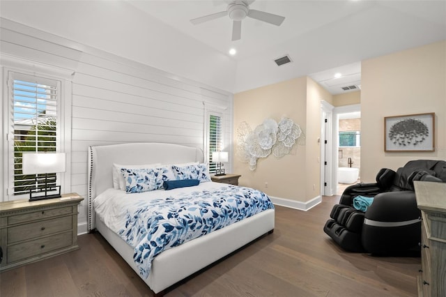 bedroom featuring ensuite bathroom, dark wood-type flooring, ceiling fan, and wood walls