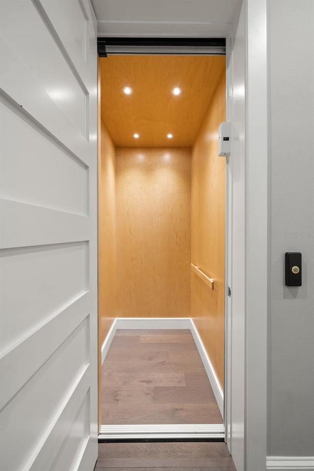 details with hardwood / wood-style flooring and elevator