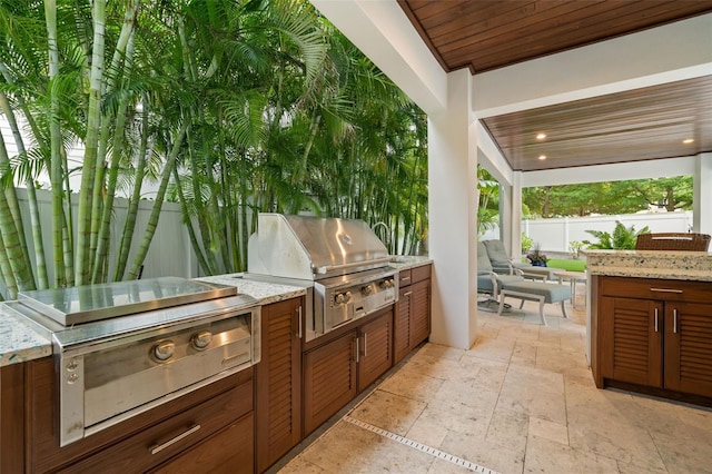 view of patio with exterior kitchen and a grill