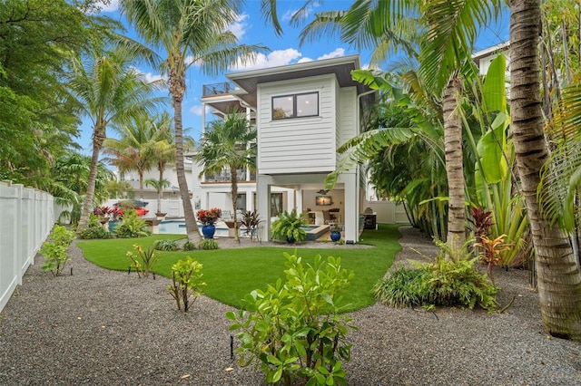 rear view of property featuring a lawn, a patio, and a balcony