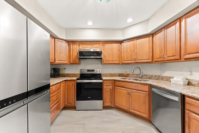 kitchen with stainless steel appliances, sink, and light stone counters