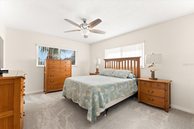 bedroom featuring light colored carpet, ceiling fan, and a textured ceiling