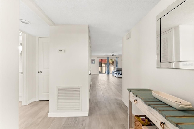 hallway featuring light hardwood / wood-style floors and a textured ceiling